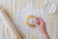 WomanÃ¢â¬â¢s hand dropping flour on ball of cookie dough, pastry cloth, wood rolling pin with cloth cover, small bowl of flour